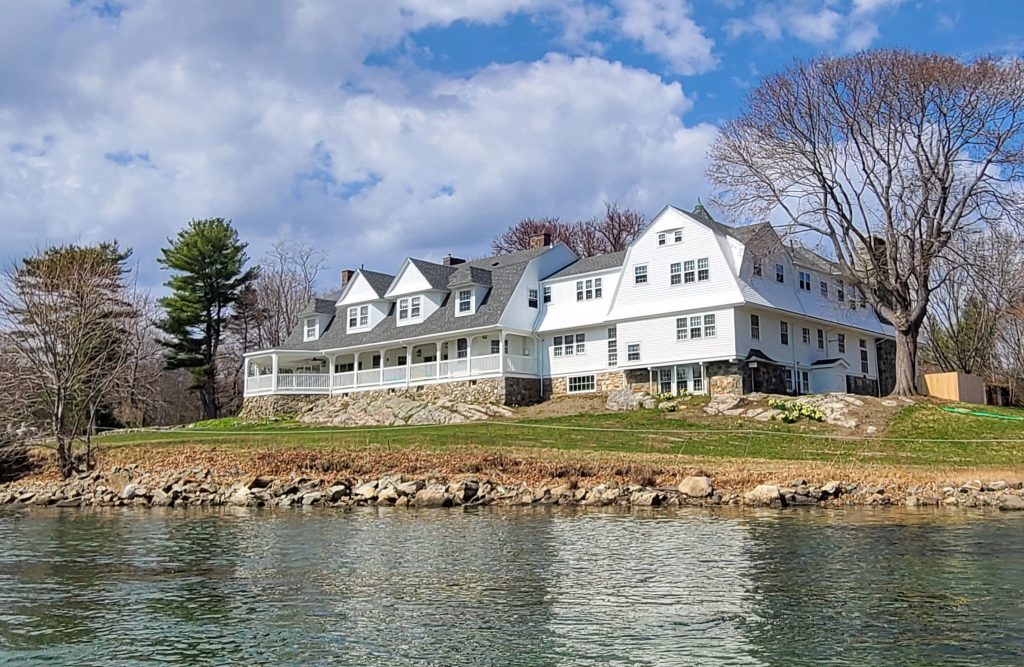 Carey Cottage, a large white building on a green hill with water in front