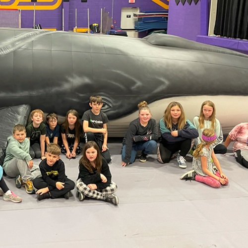 Young students sitting in front of a giant inflatable whale