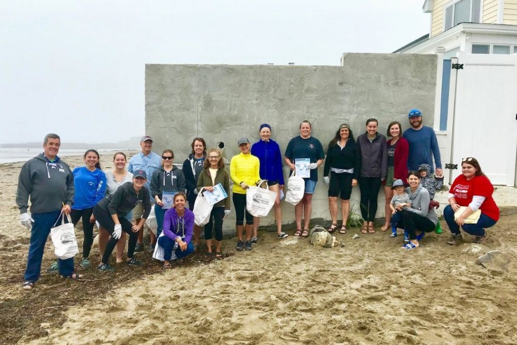 A group of people at the beach with bags of trash